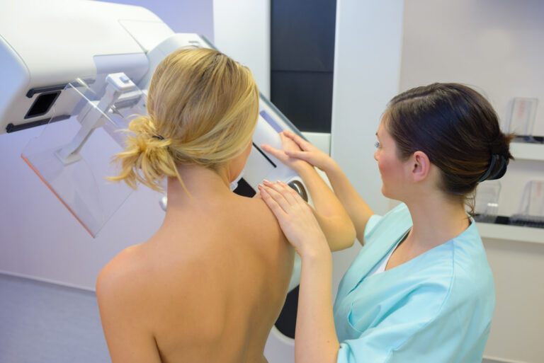 Doctor assisting patient undergoing mammogram