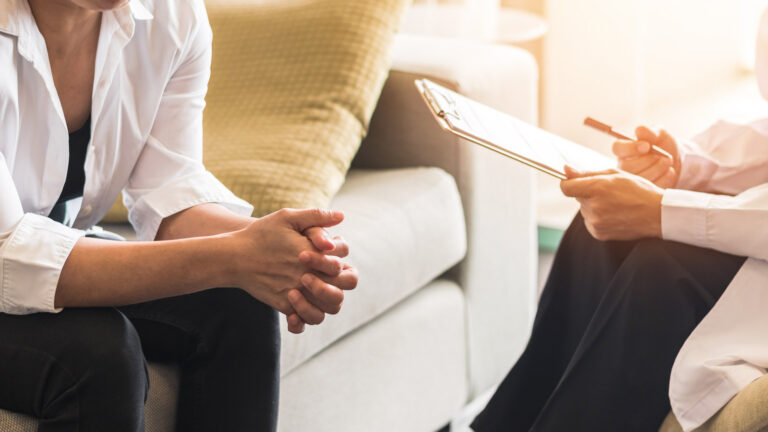 Doctor consulting and woman patient on sitting on a couch.